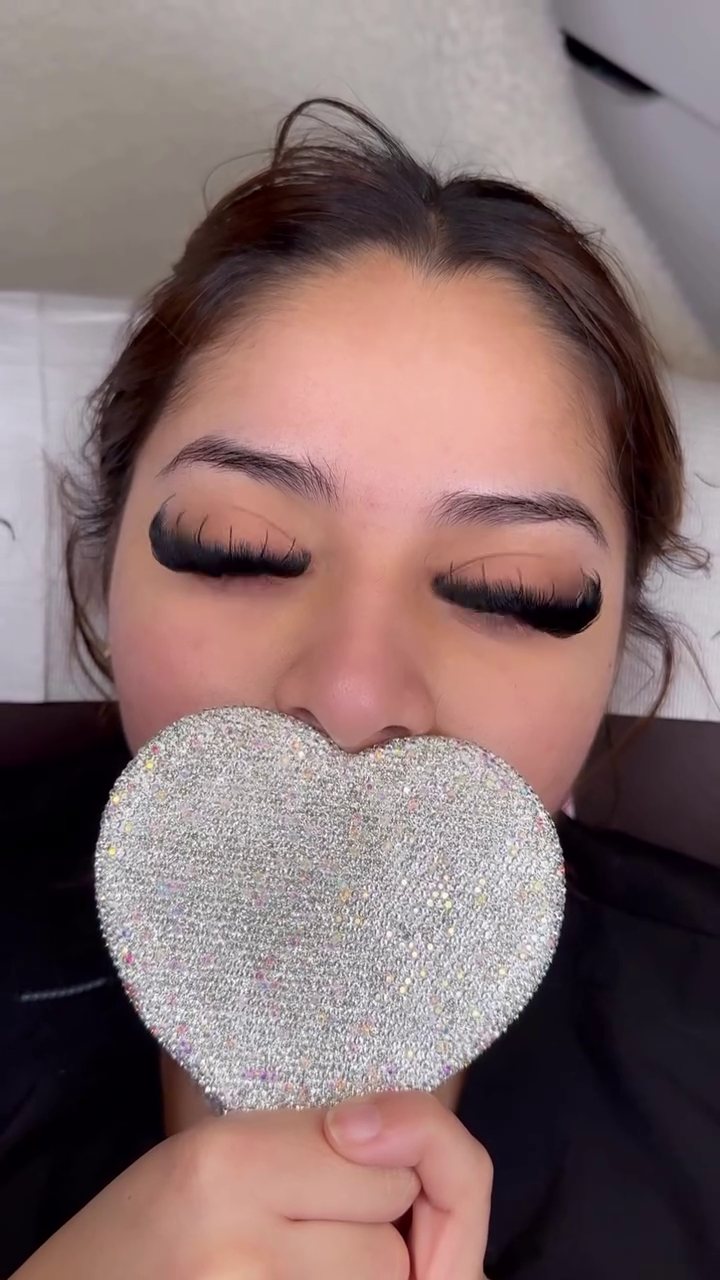 Client holding a sparkly heart mirror under a fresh volume set